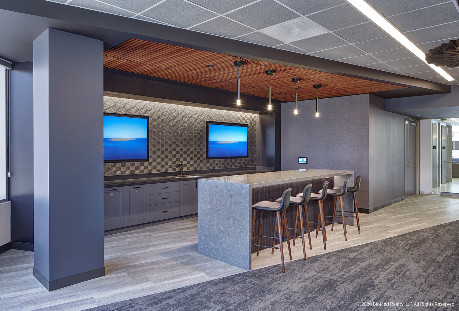 break room kitchen with textured brass-tone tile and a seating island with 5 chairs