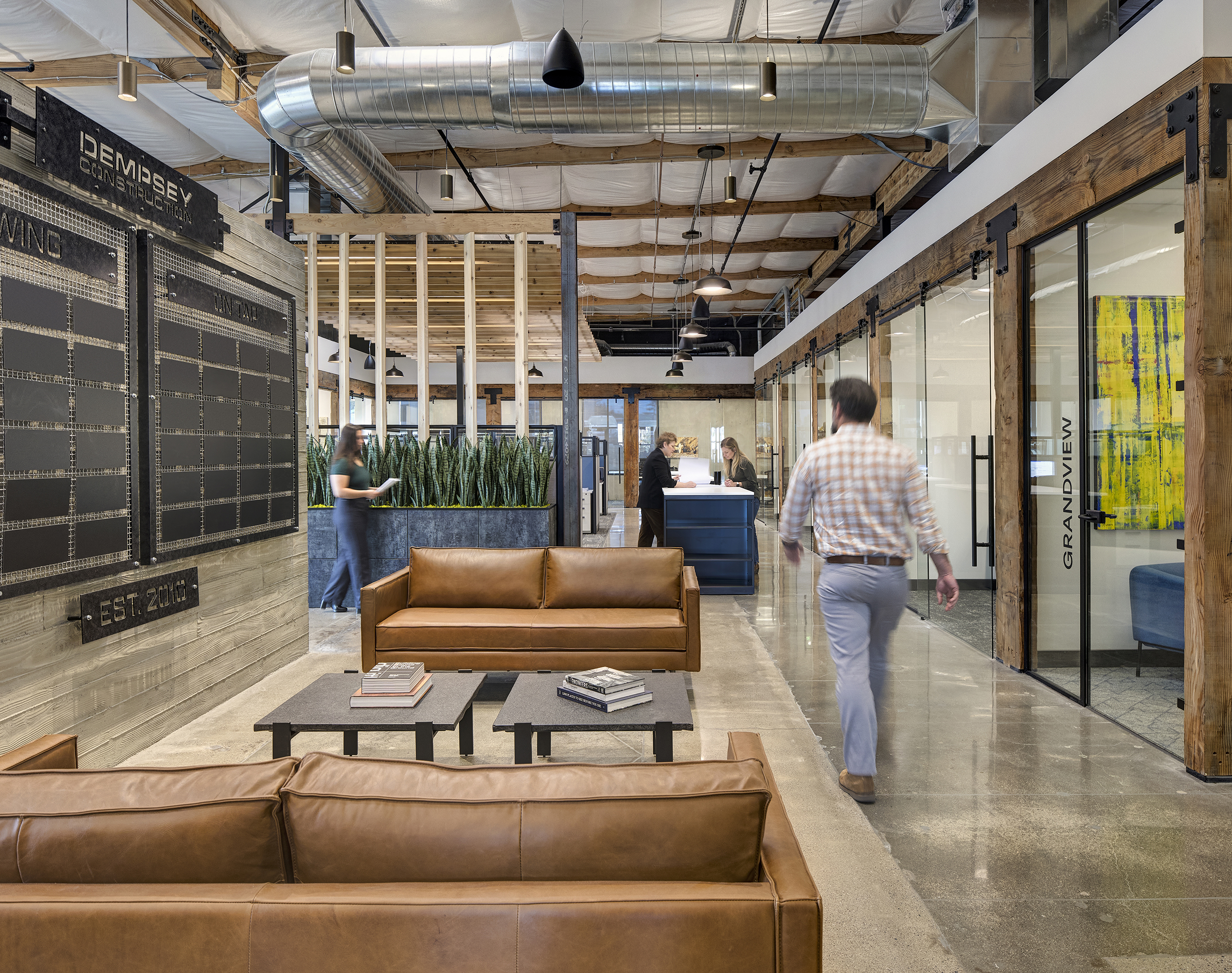 Open office layout with collaborative workstations and natural lighting at Dempsey Construction, designed by ID Studios