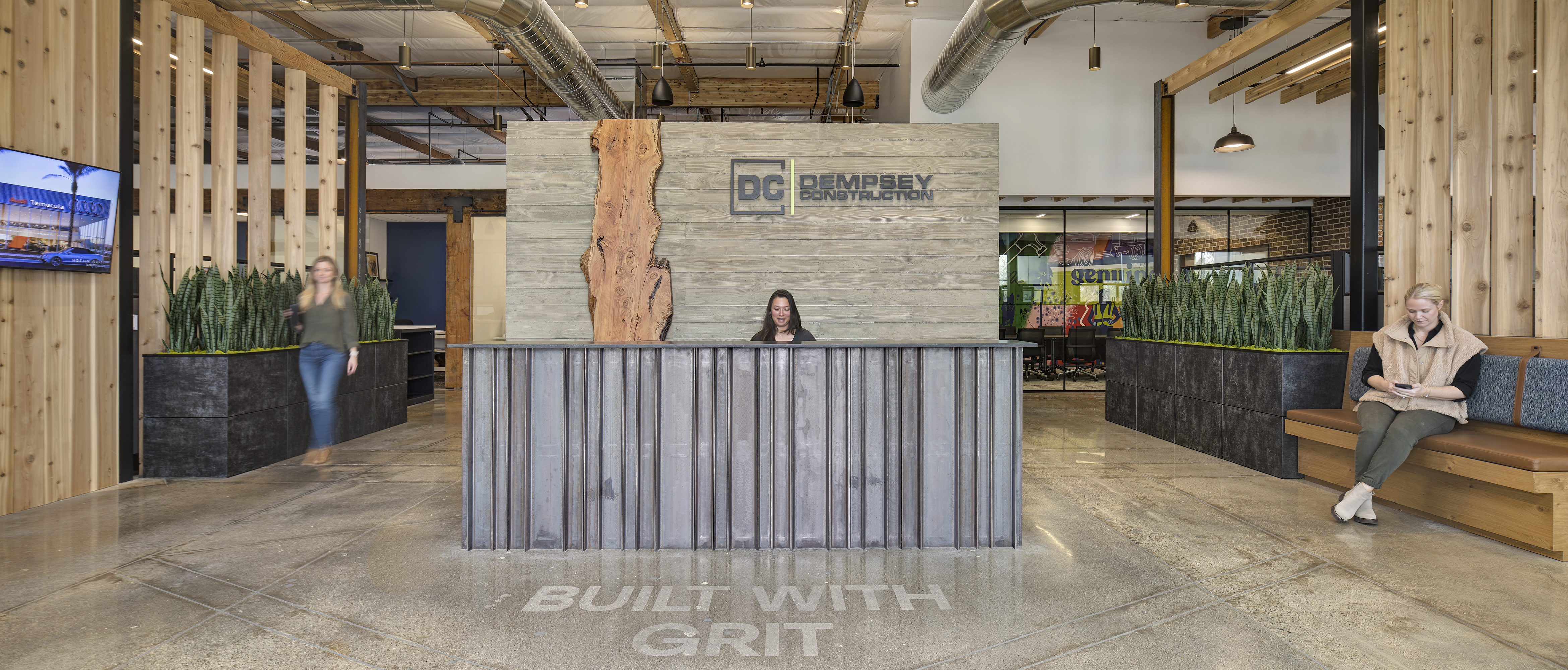 Modern reception area at Dempsey Construction office with branded signage, warm materials, and collaborative design elements.